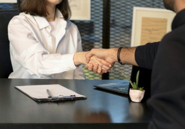 a man and a woman shaking hands in front of a laptop